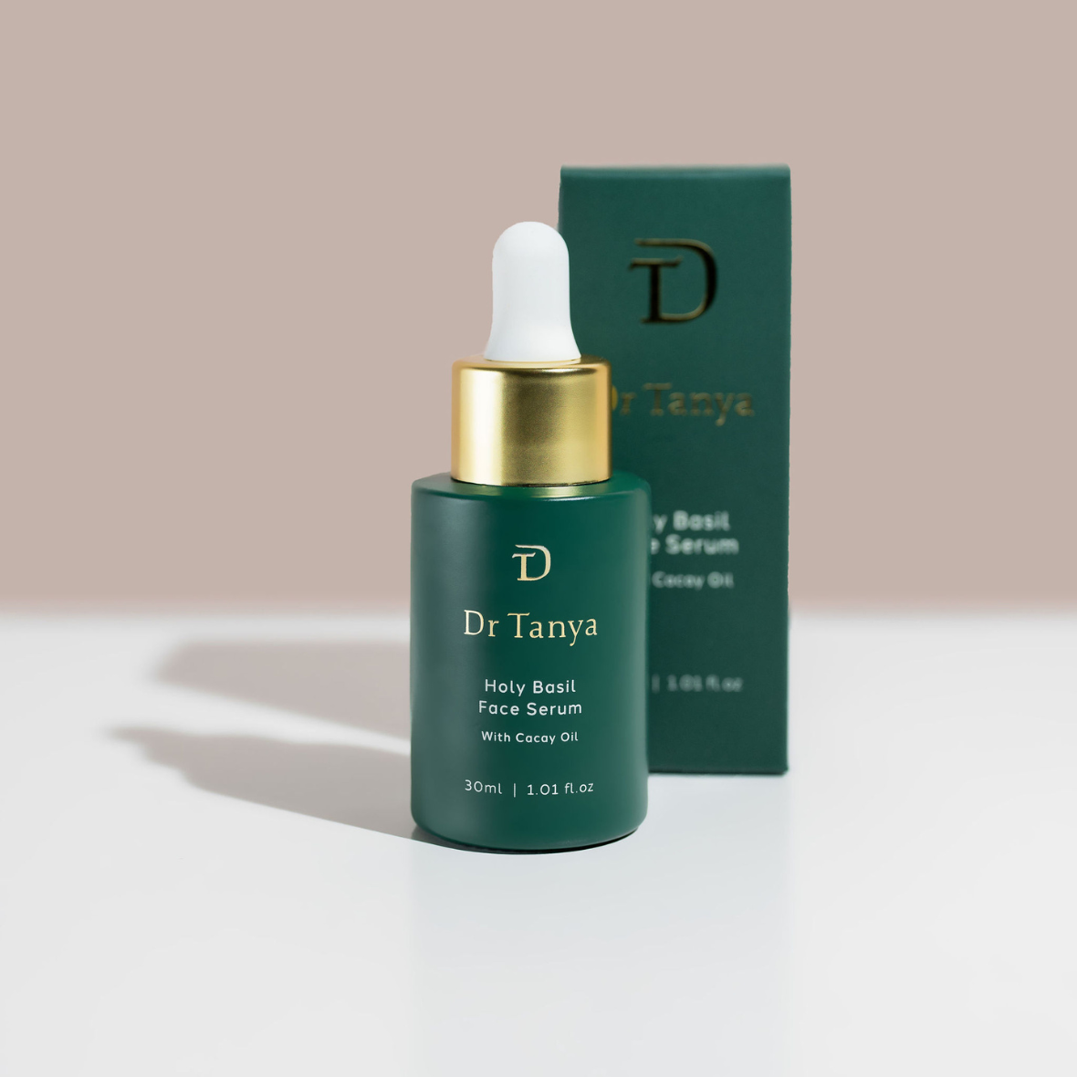 A small emerald green bottle of face serum in front of its green product box