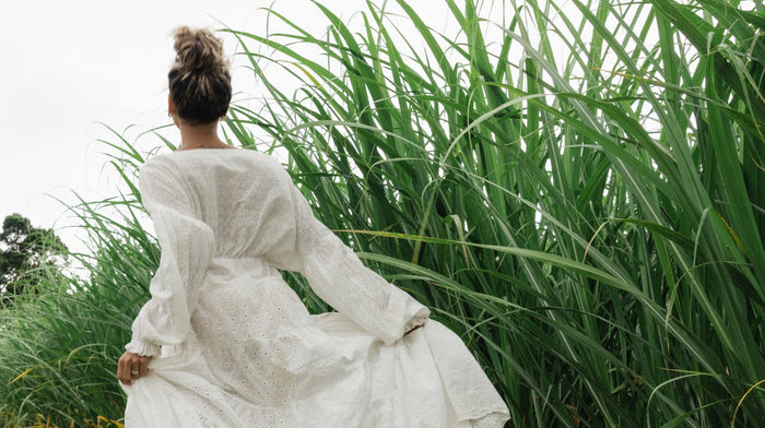 A woman in a white dress runs in a field of long grass