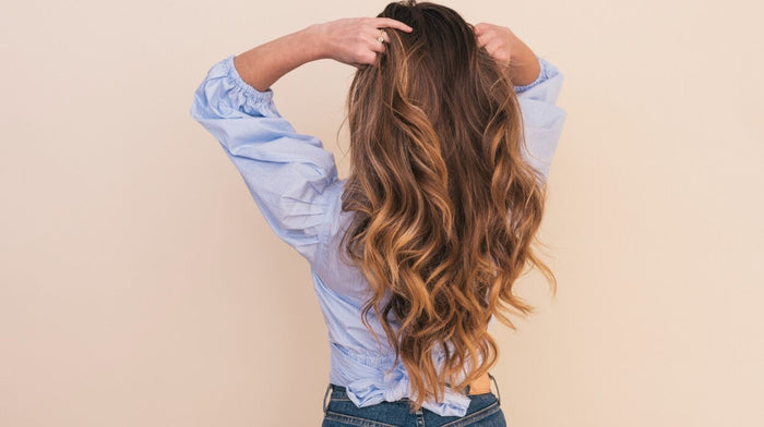 Woman combing her hands through her long light brown hair