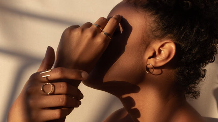 A woman facing the side with her hands covering her face