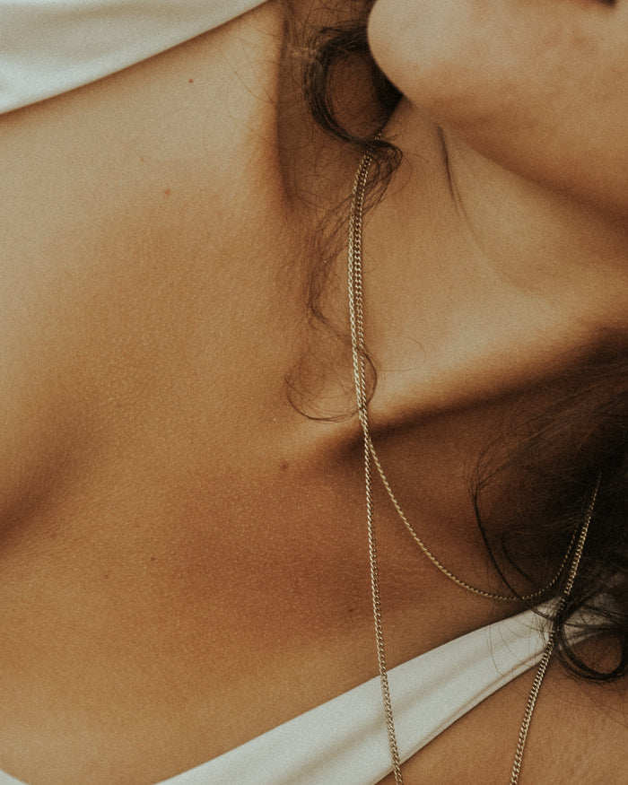 A woman's neck with a gold necklace