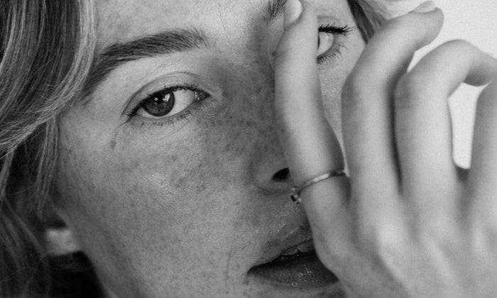 Black and white image of a lady touching her face